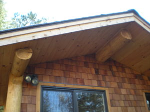 Log roof supportsStone and cedar Sauna building