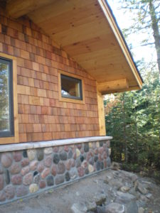 Log roof supports Stone and cedar Sauna building
